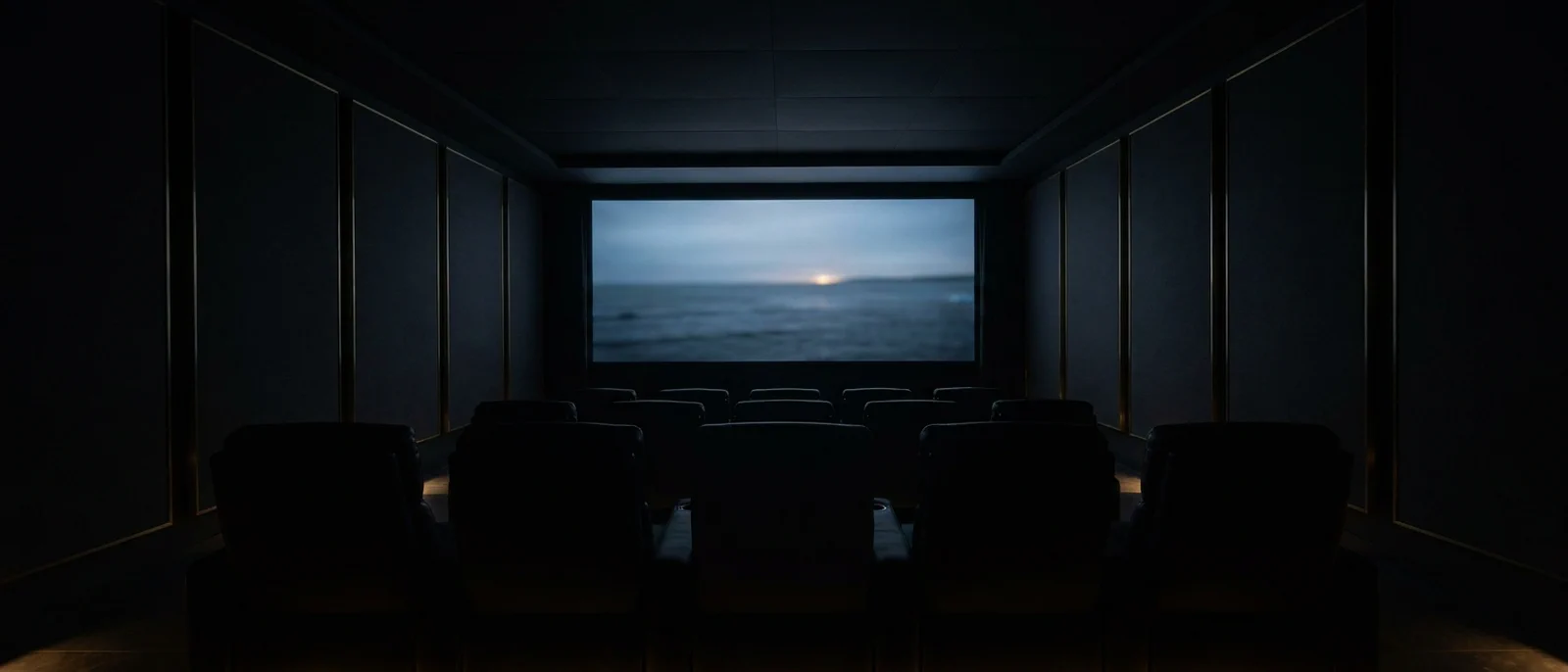 A dark cinema room dissolving into blackness, lit only by the distant glow of the screen